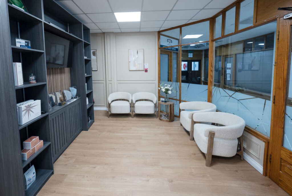 the waiting room at Claire Hughes Dental, with white comfortable chairs and a shelf with awards